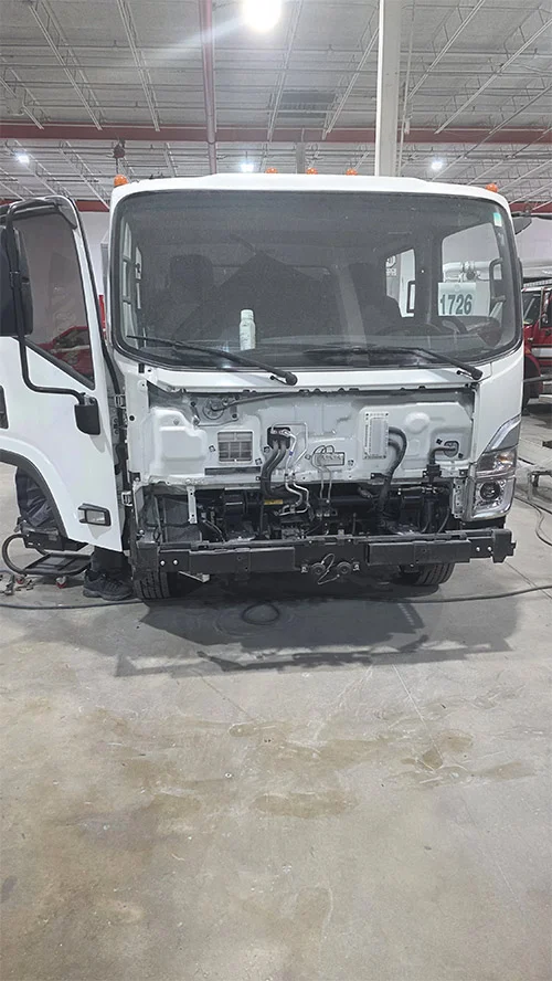 Isuzu truck cab with front body panels removed for repair in Pompano Beach, FL