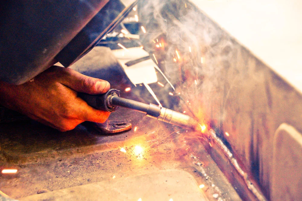 Welding torch repairing cracked steel crossmember