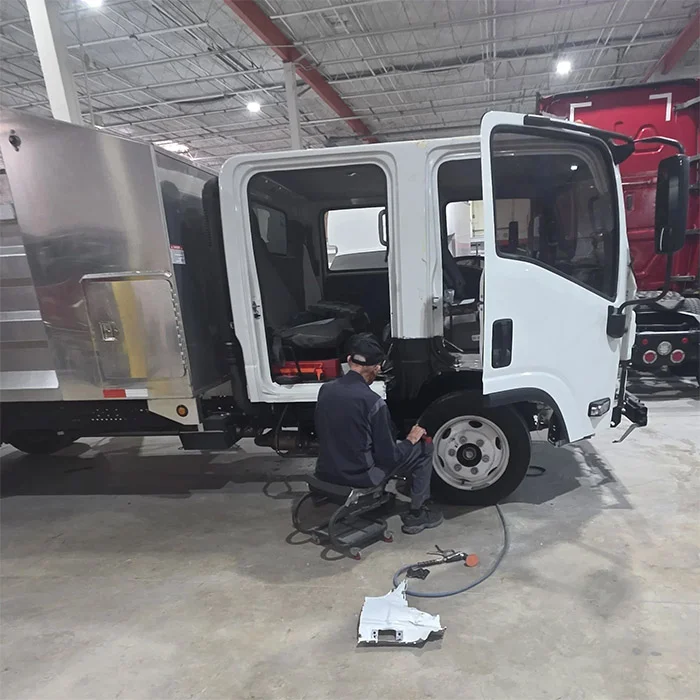 Technician repairing an Isuzu box truck cab in Pompano Beach, FL