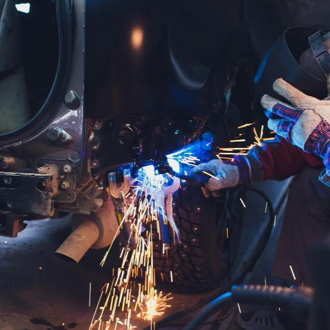 Technician welding beneath heavy truck frame