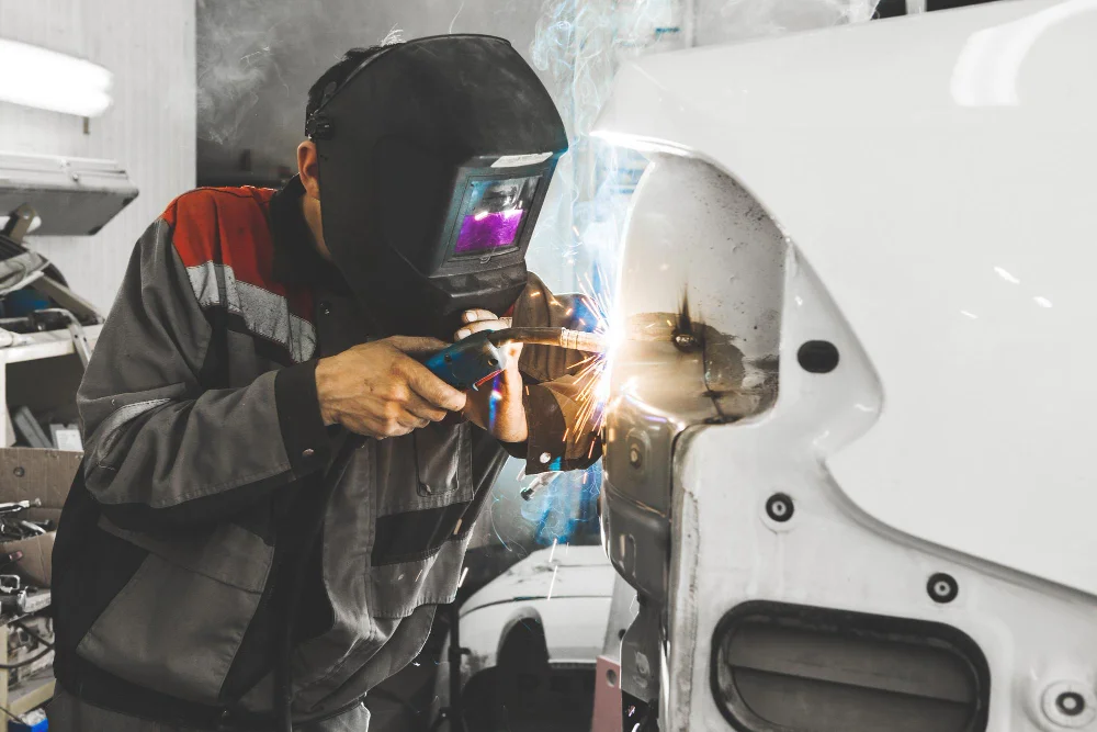 Welder repairing white truck body panel