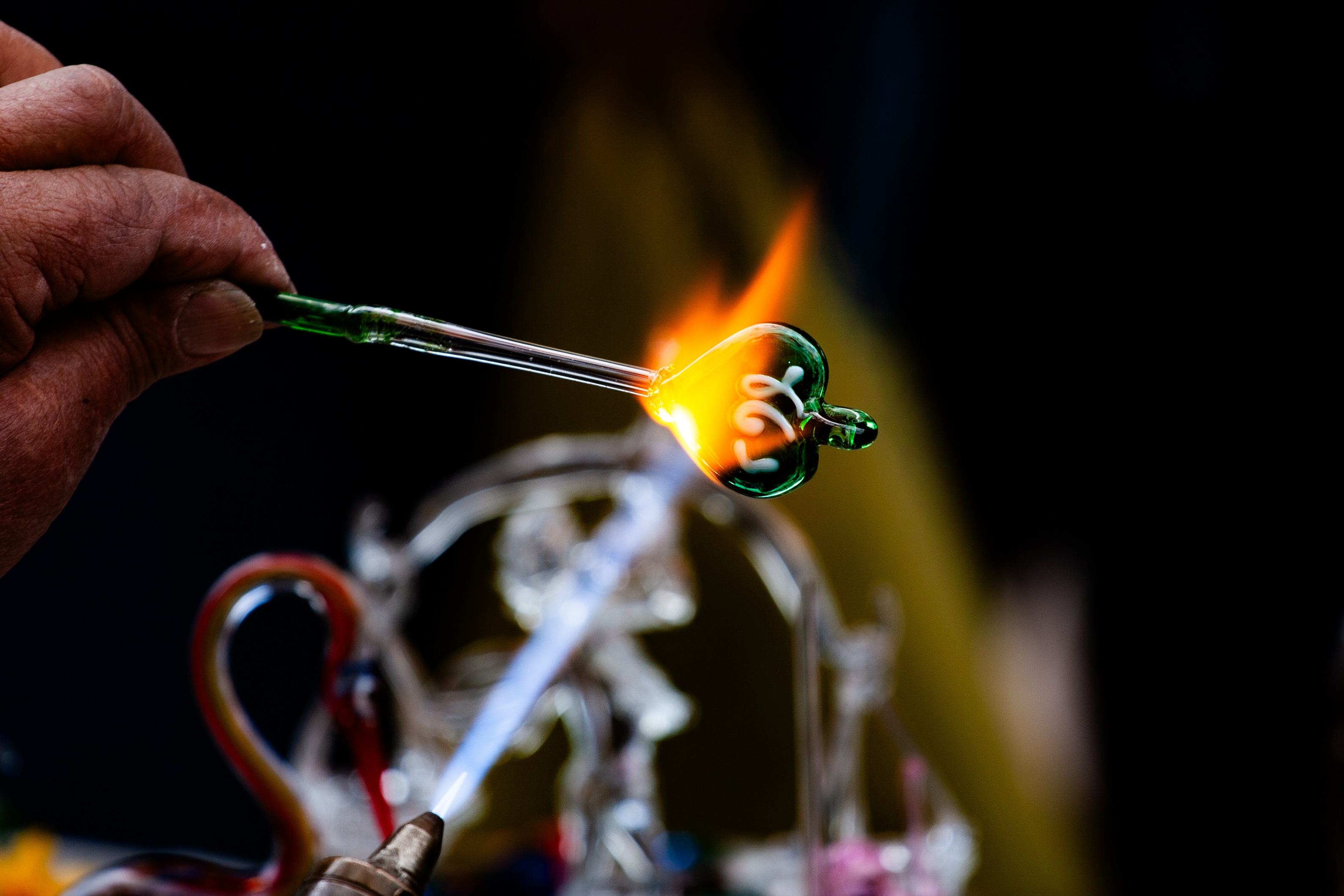 A close-up of an artisan shaping a glass heart over a flame, showcasing intricate craftsmanship in progress. Tel Aviv, Israel