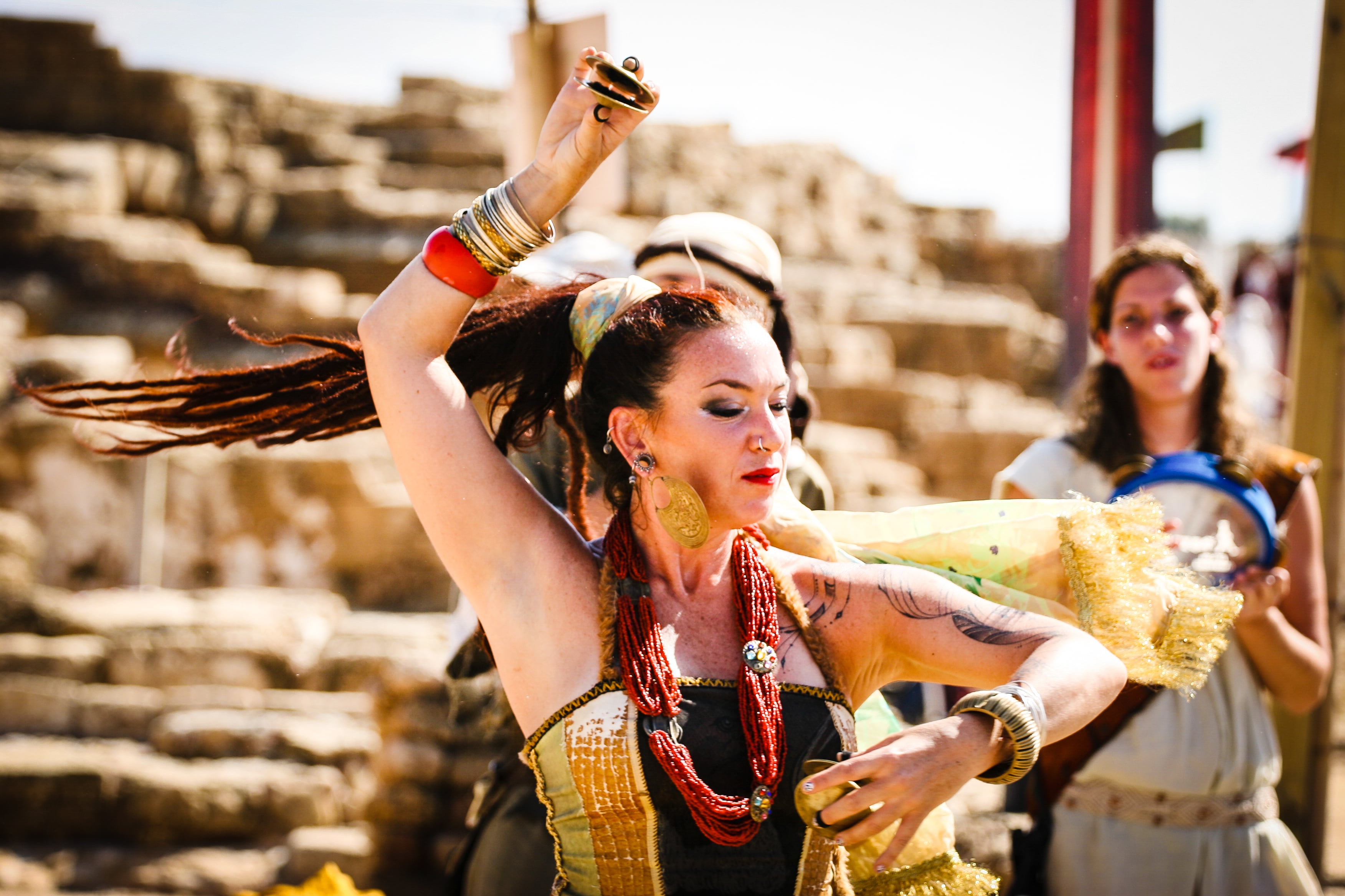 A dancer in traditional dress performs energetically against the ancient stone walls of Caesarea Port. Caesarea Port, Israel