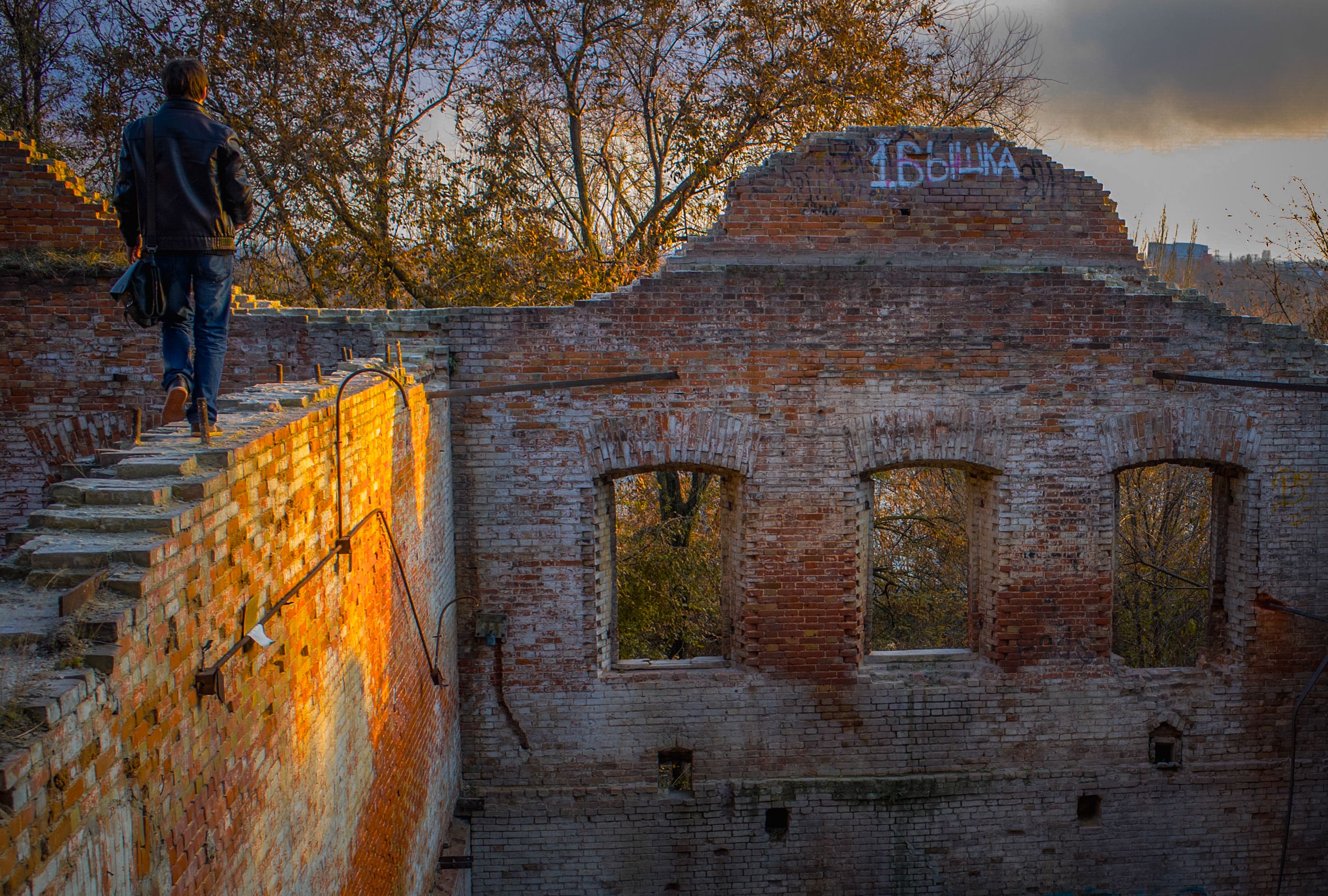 A man walks along a crumbling wall in Rostov, Russia, blending the rustic beauty of ruins and history. Rostov-On-Don