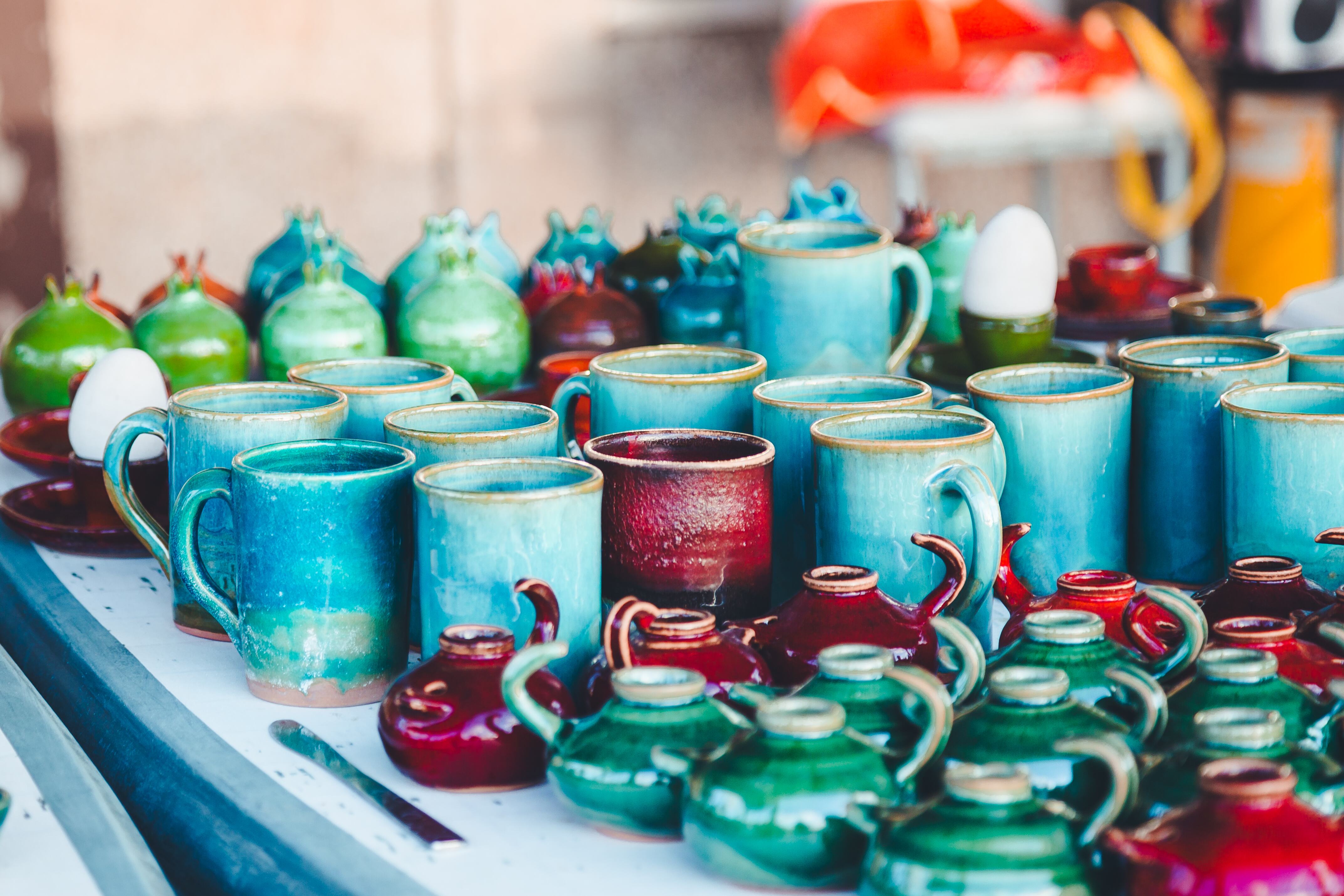 An assortment of colorful ceramic mugs and pots, primarily in shades of blue and green, arranged on a table. Haifa, Israel