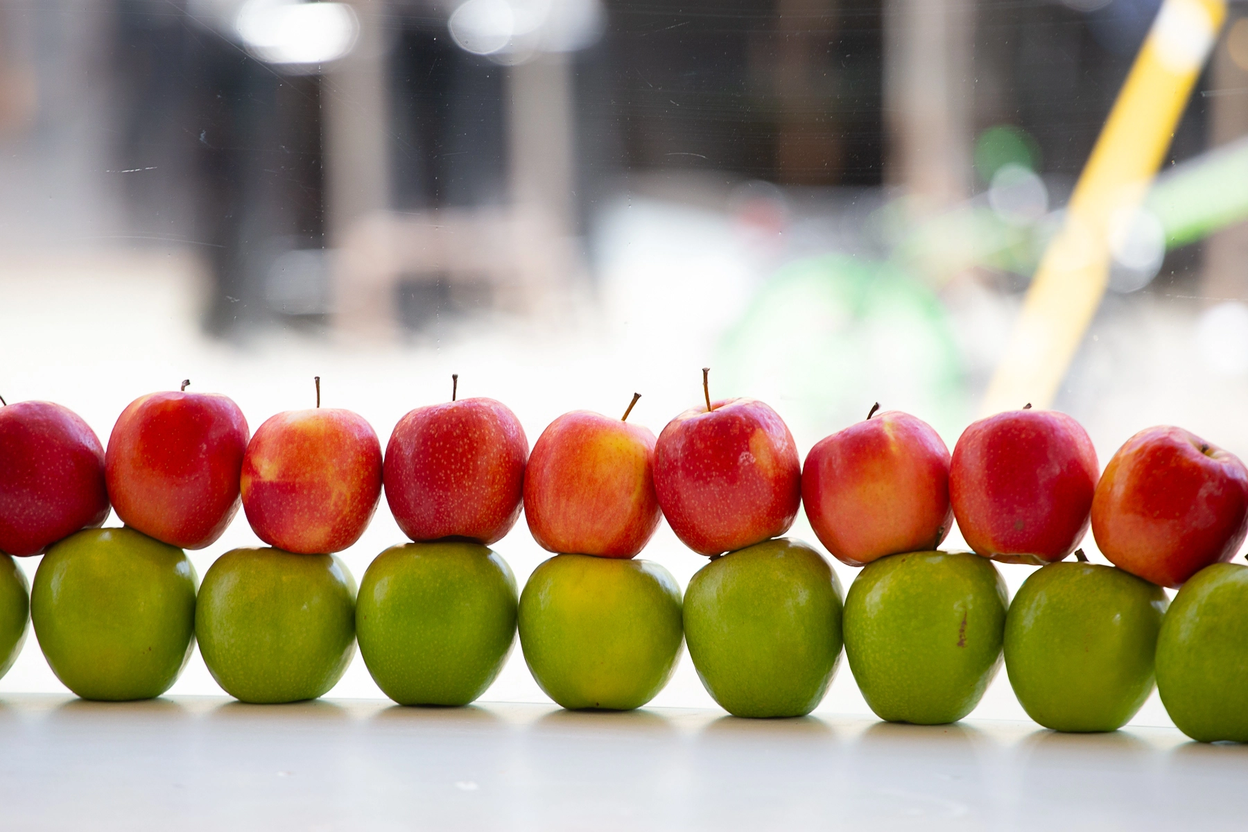 A neat arrangement of red and green apples stacked in two rows on a surface.Tel Aviv, Israel