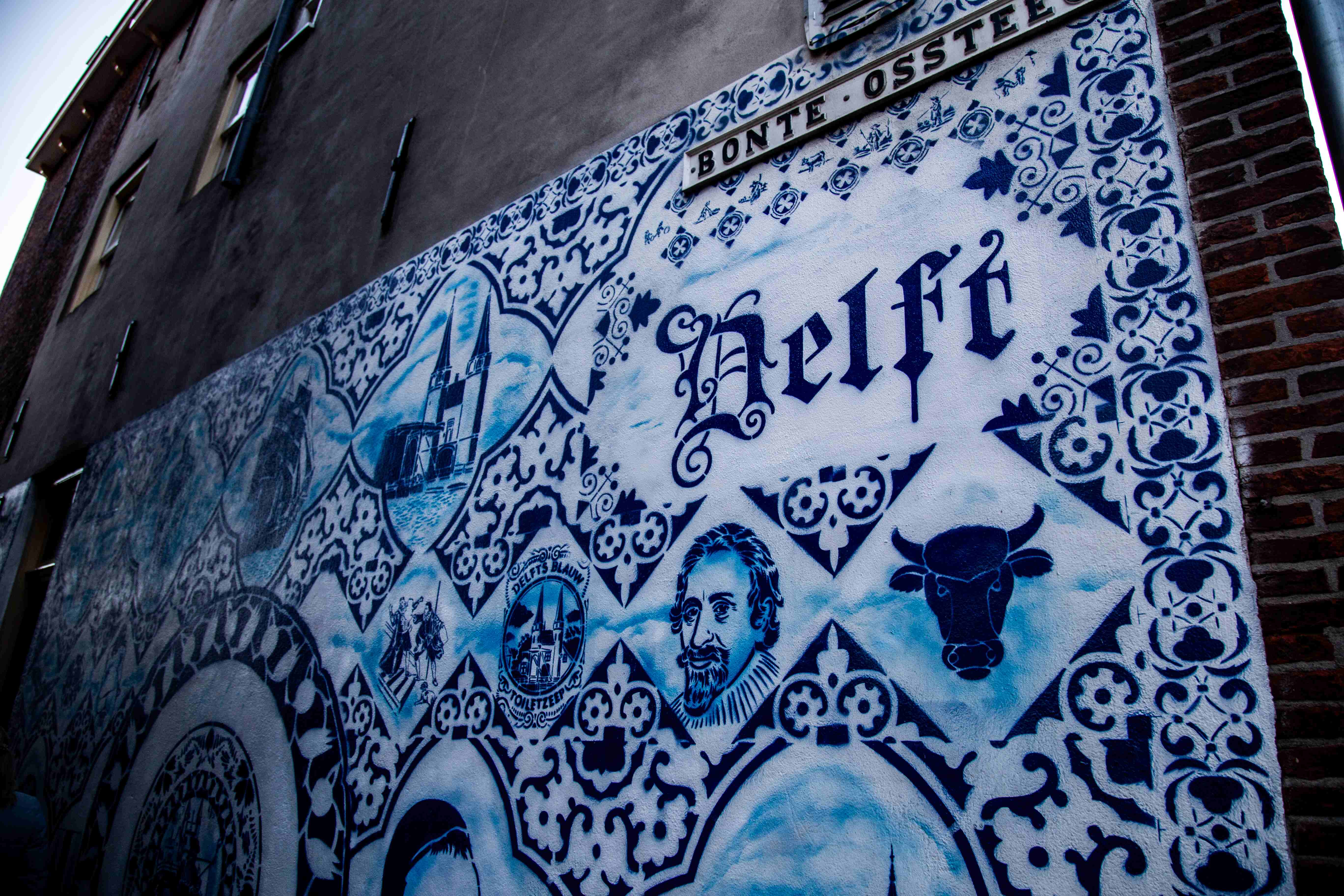 A detailed mural in traditional Delft blue style, featuring portraits, symbols, and landmarks of Delft. Delft, Netherlands