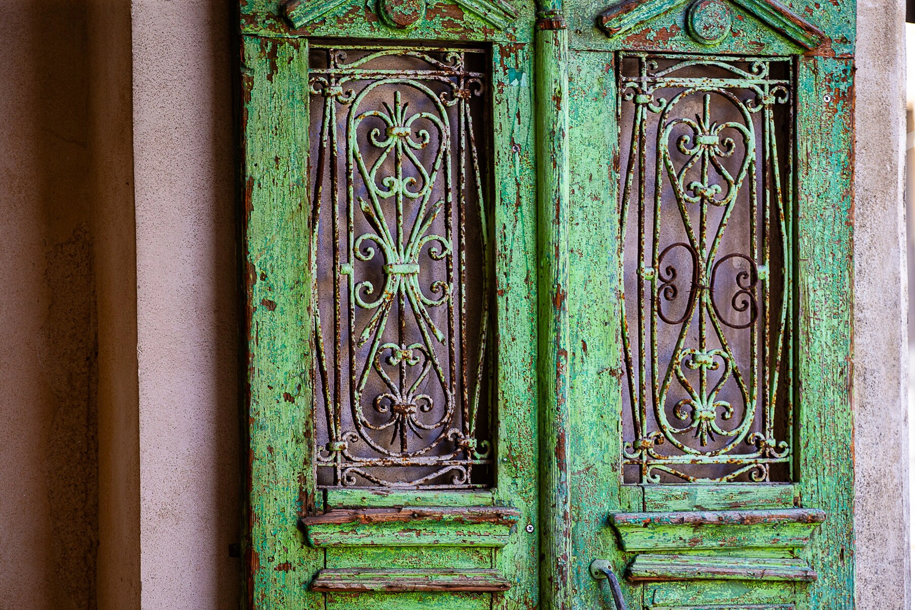 An old green wooden door with ornate ironwork details, showing signs of age and peeling paint. Tel Aviv, Israel