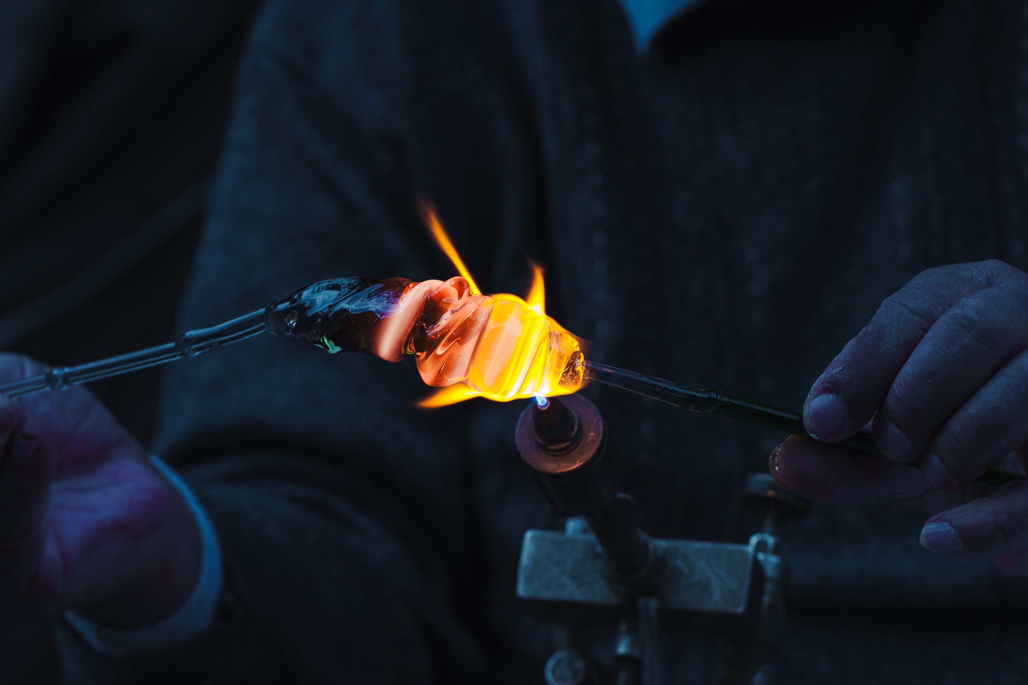 A close-up of hands carefully shaping molten glass with fire in a glassblowing process. Tel Aviv, Israel