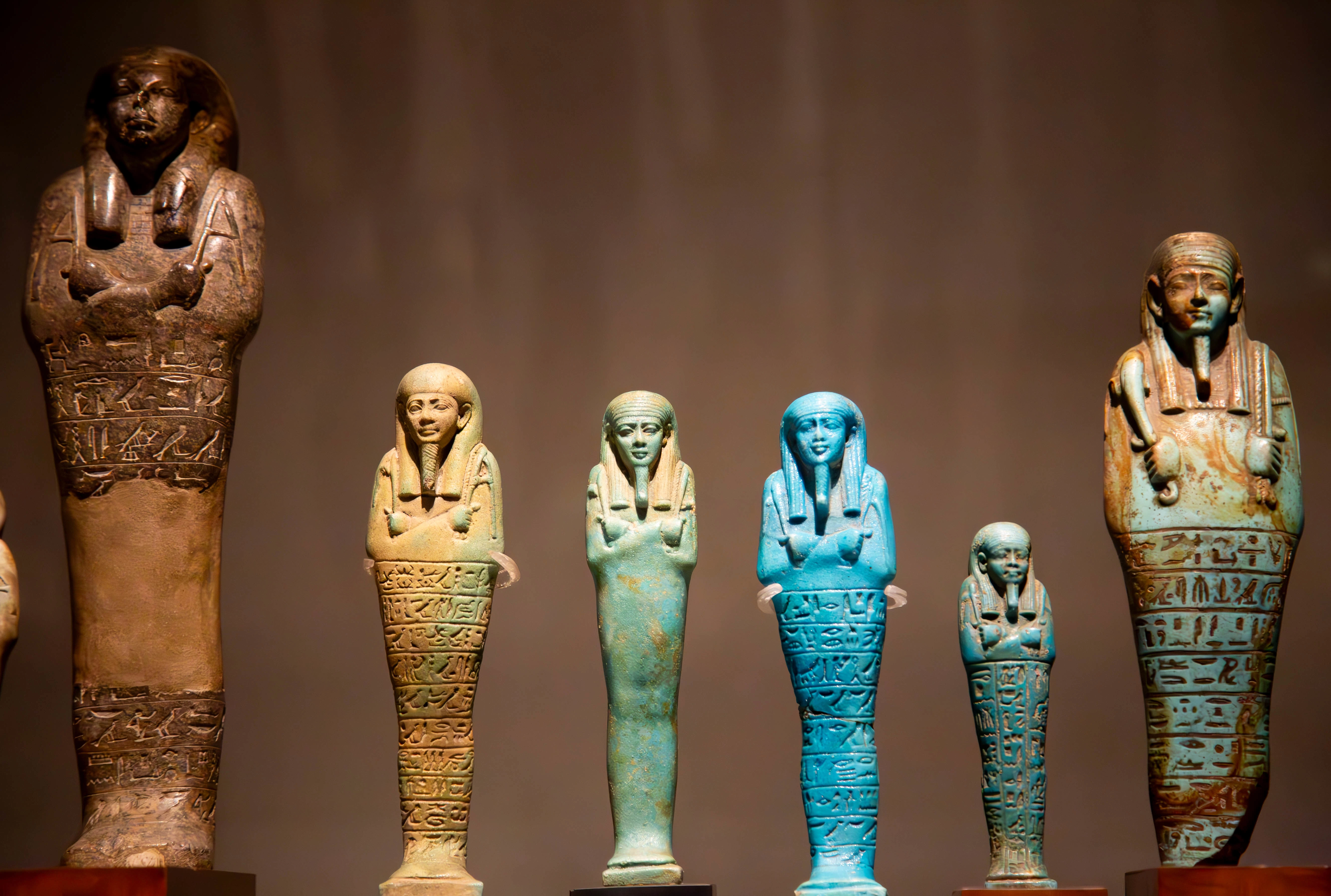 A collection of Egyptian ushabti statues in various colors and sizes, displayed in a museum. Turin, Italy