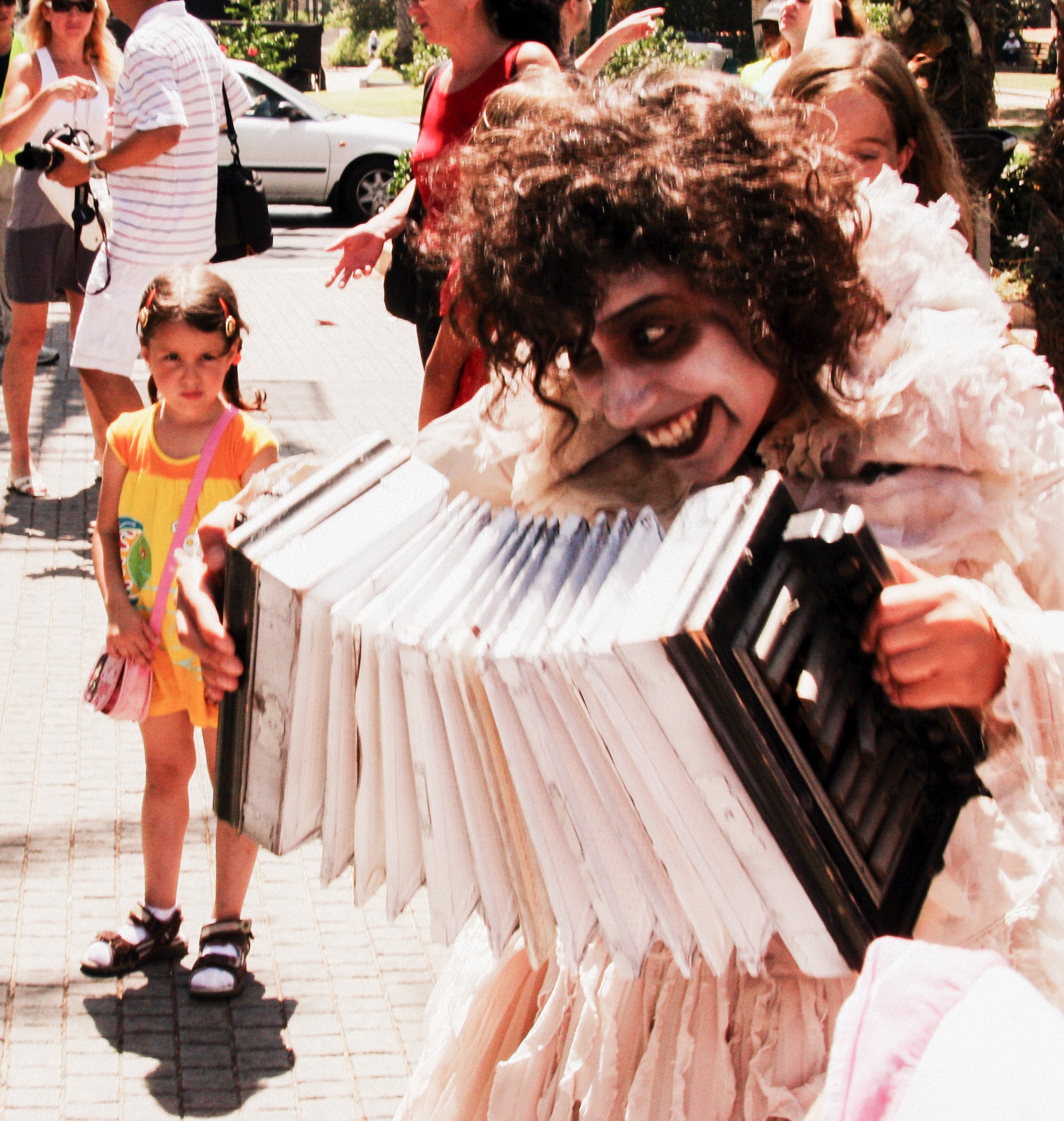 An upward view of Azrieli ToPerformer with dramatic makeup and an accordion entertains festival crowd.Street Festival, Ramat HaSharon, Israelwers creates a geometric composition of grids and sky, symbolizing modern architectural elegance and strength. Street Festival, Ramat HaSharon, Israel