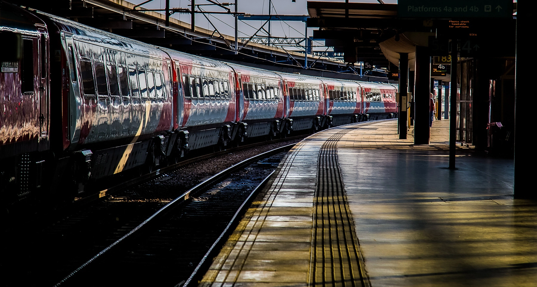 A train pulling into Leeds Station, with reflections on the train's windows and a curved platform. Leeds,Great Britain