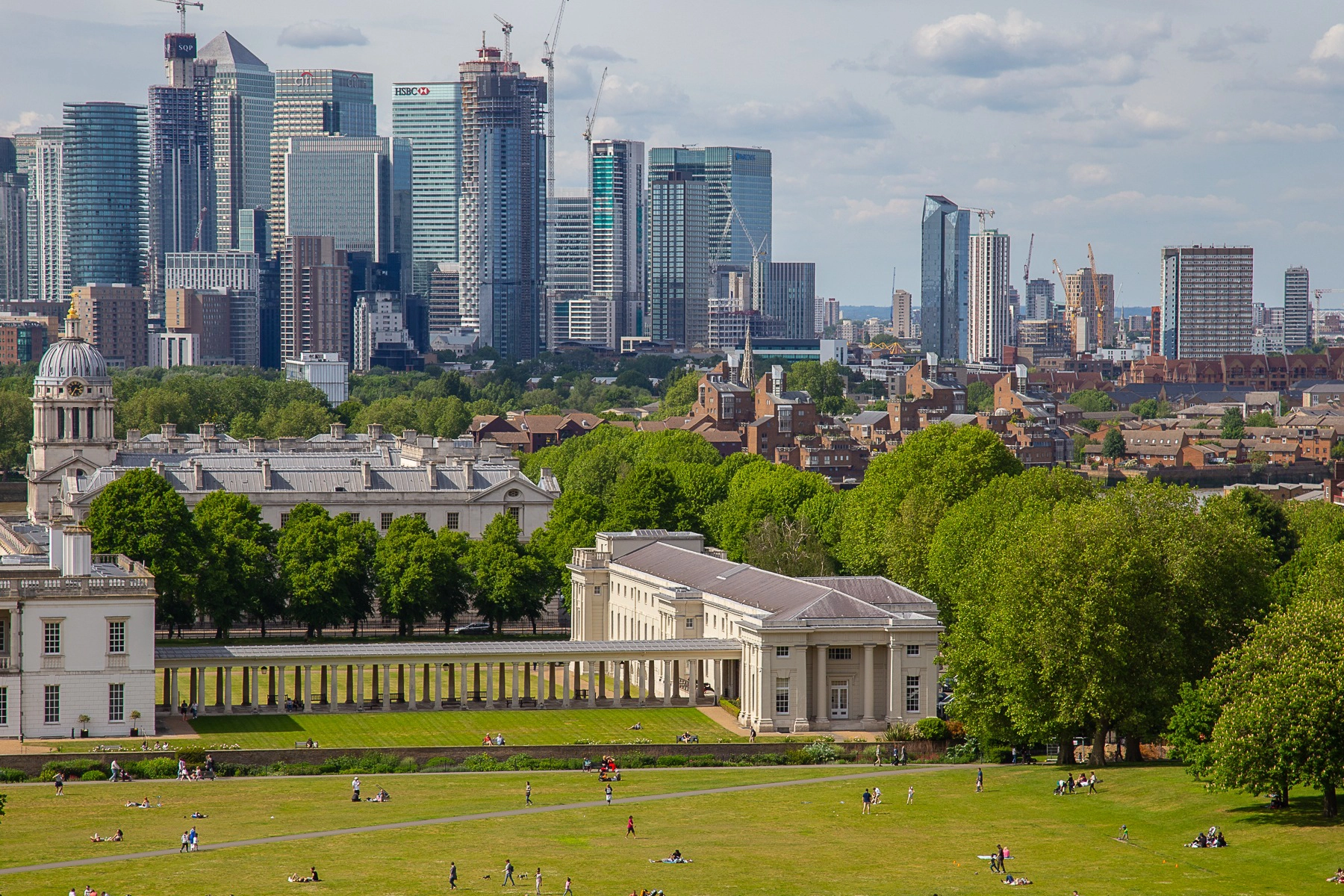 Overlooking the vibrant green lawns of Greenwich Park with Canary Wharf's towering modern skyline in the distance. London, Great Britain