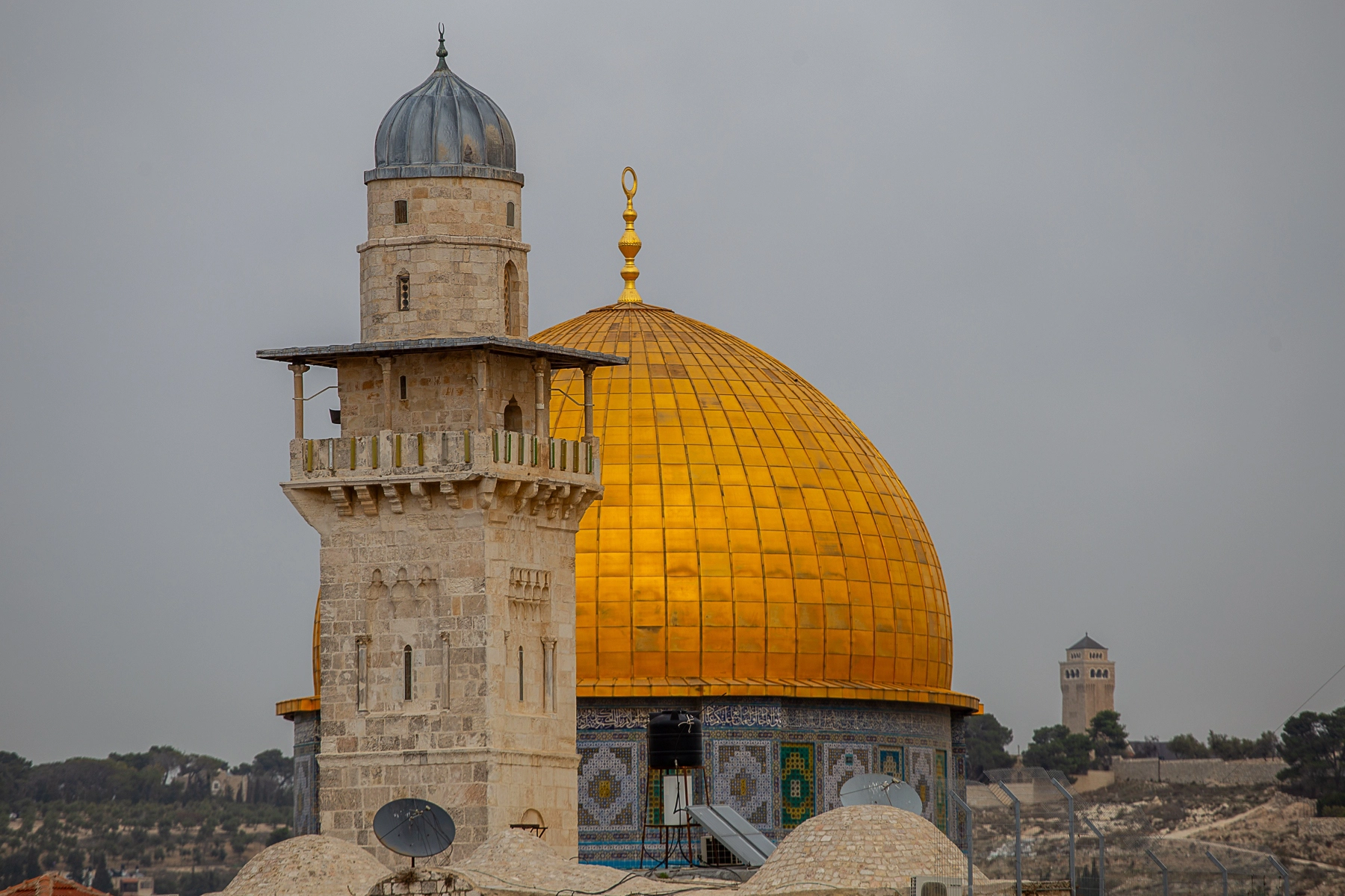 A stunning view of the golden Dome of the Rock with the minaret of a nearby mosque in the foreground, set against a cloudy sky. Hertzliya, Israel