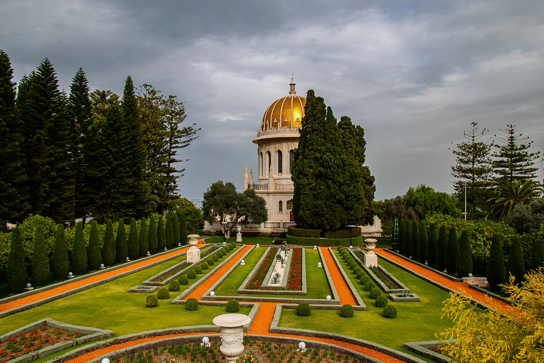 A close-up view of the Shrine of the Báb in the Bahá'í Gardens, surrounded by manicured lawns, hedges, and paths lined with vibrant greenery. Haifa, Israel