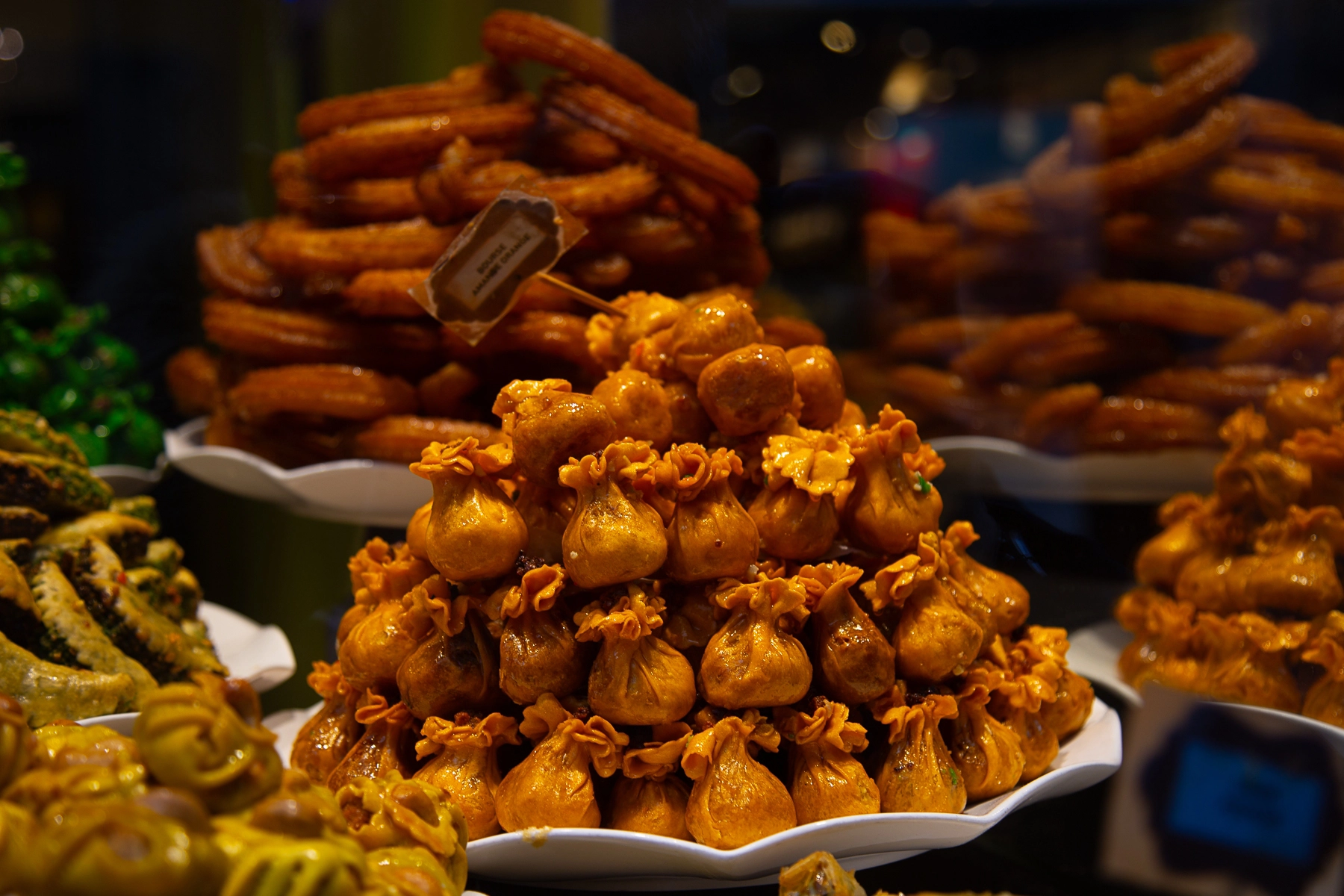 A variety of golden pastries, including churros and filled dough pouches, arranged in a shop display. Brussels, Belgium