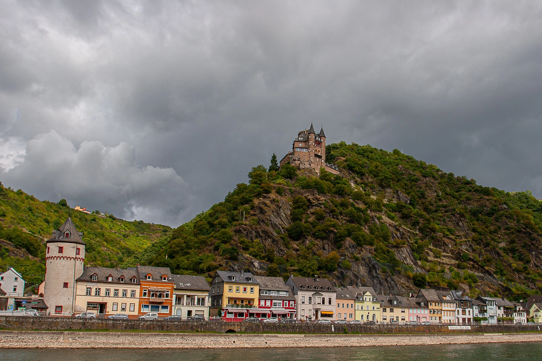 A view of the historic Marksburg Castle perched on a hill, overlooking a small town. Koblenz, Germany