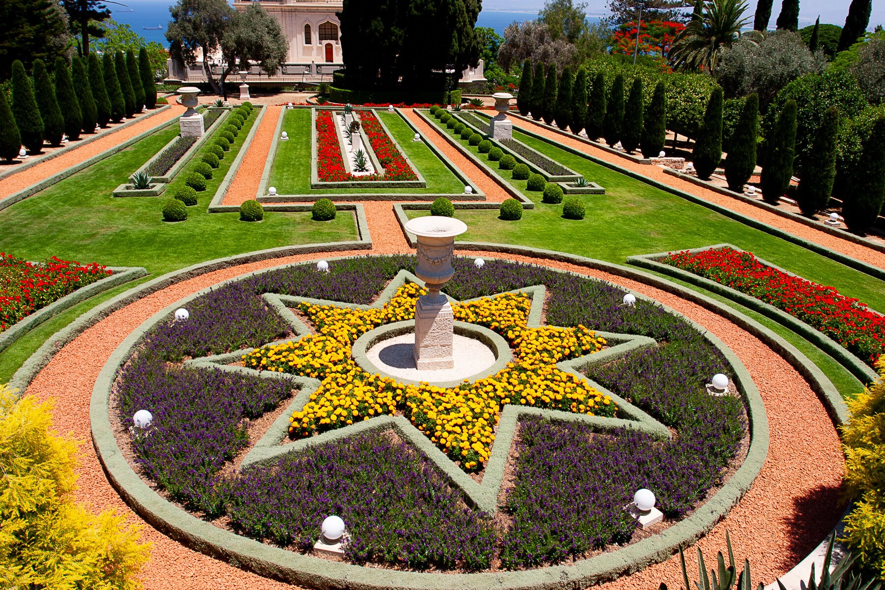 The Bahá'í Gardens in Haifa, featuring beautifully manicured flower beds, lush green lawns, and geometric designs with a sea view. Haifa, Israel