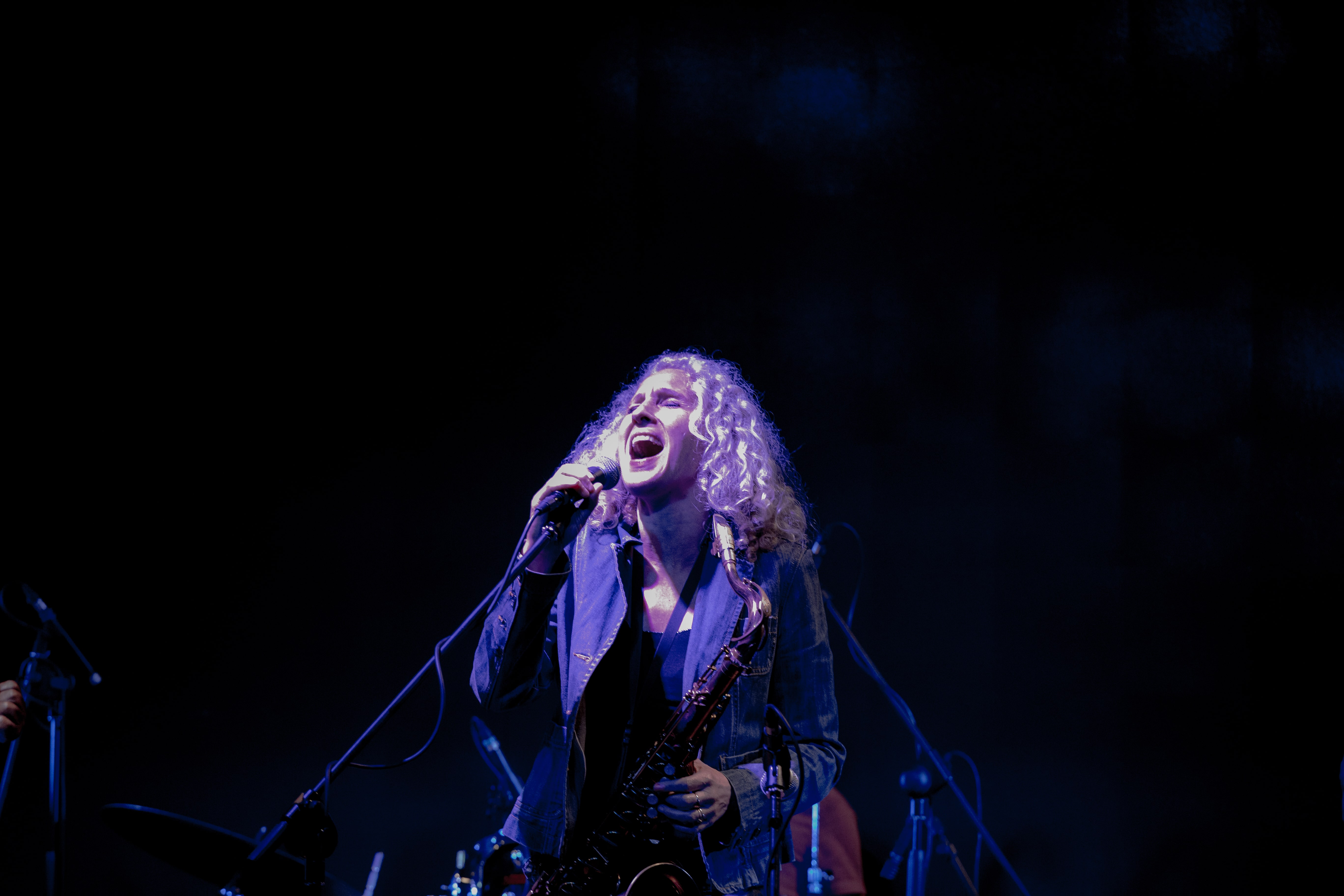 A female saxophonist passionately sings into the microphone during a live performance. Tel Aviv, Israel