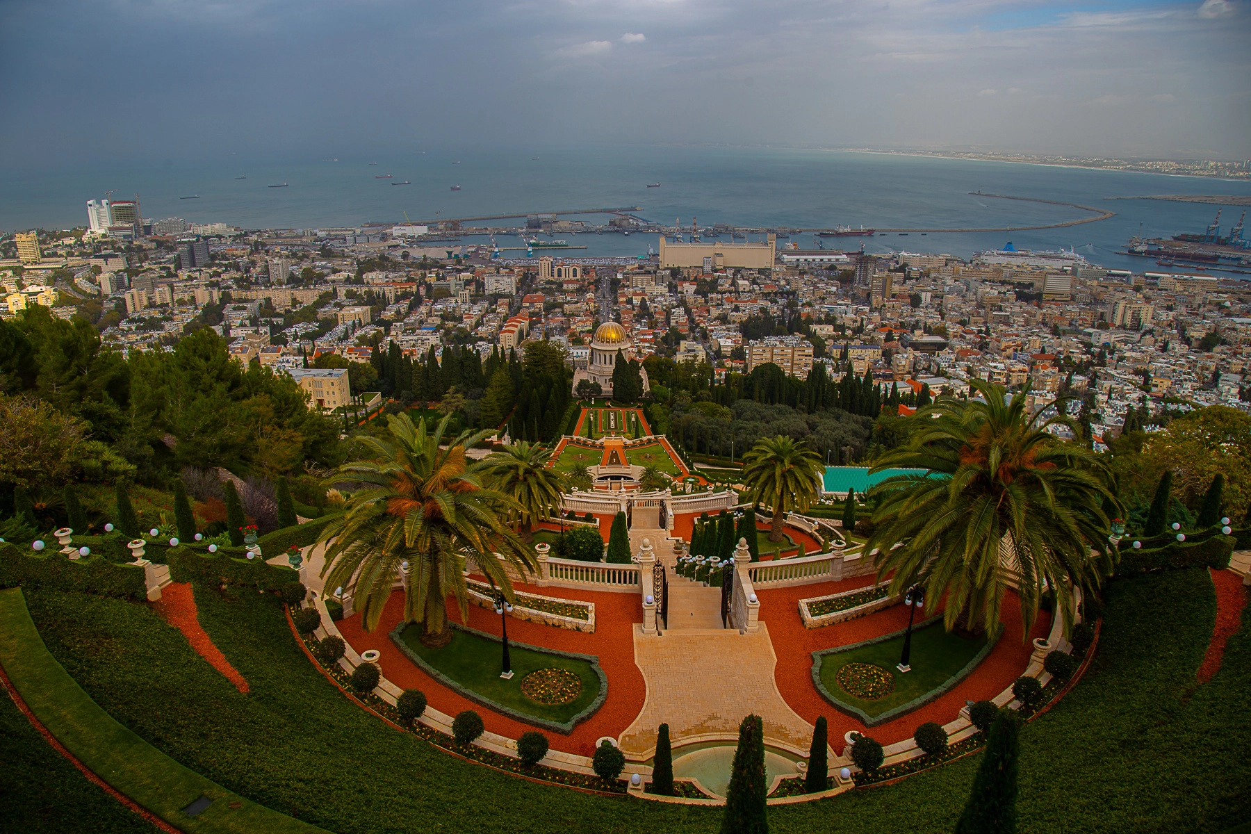 The Bahá'í Gardens in Haifa, featuring beautifully manicured flower beds, lush green lawns, and geometric designs with a sea view. Haifa, Israel