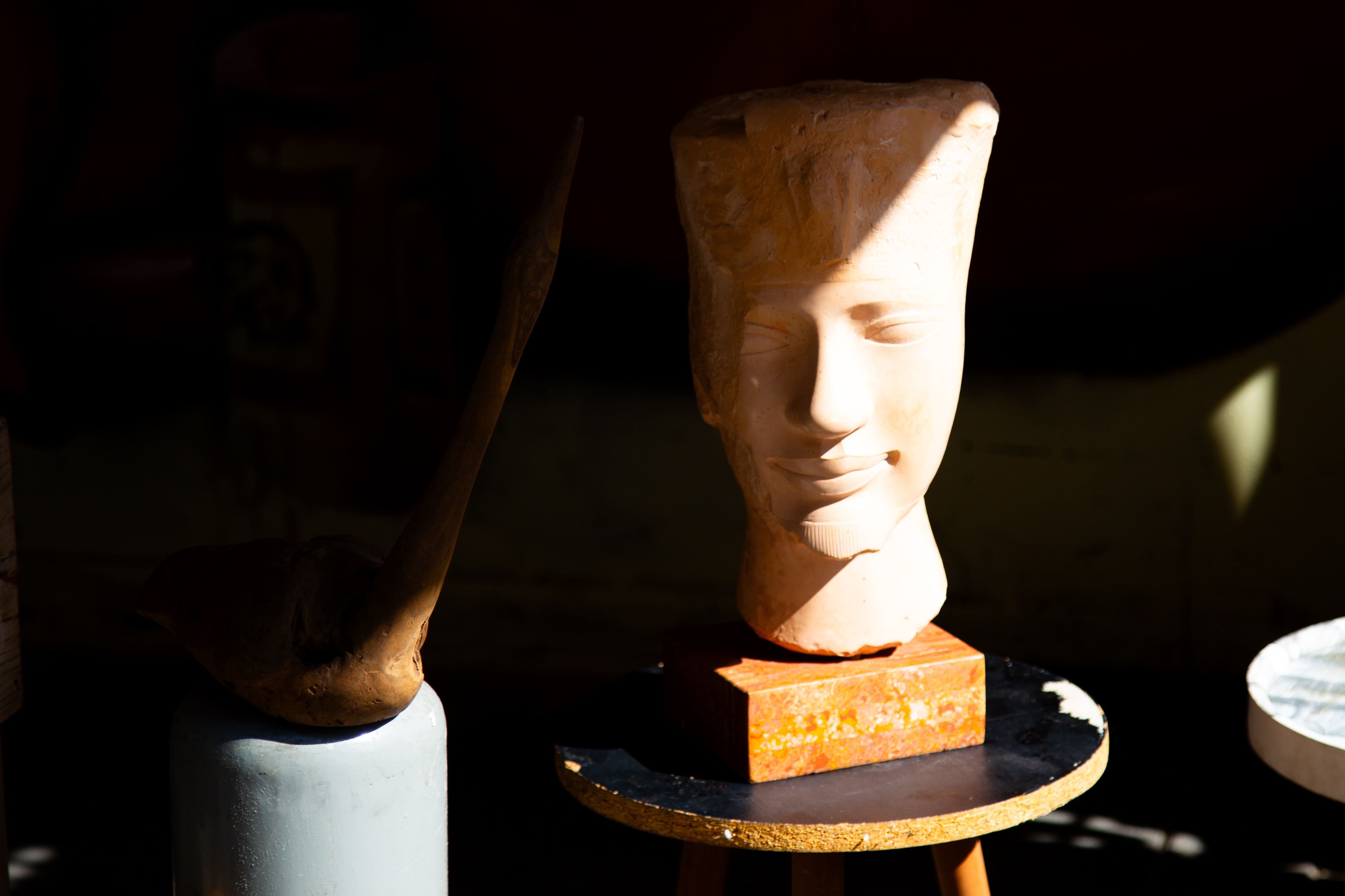 A stone bust displayed in soft lighting at a flea market, casting shadows on a rustic background. Flea Market Tel Aviv, Israel