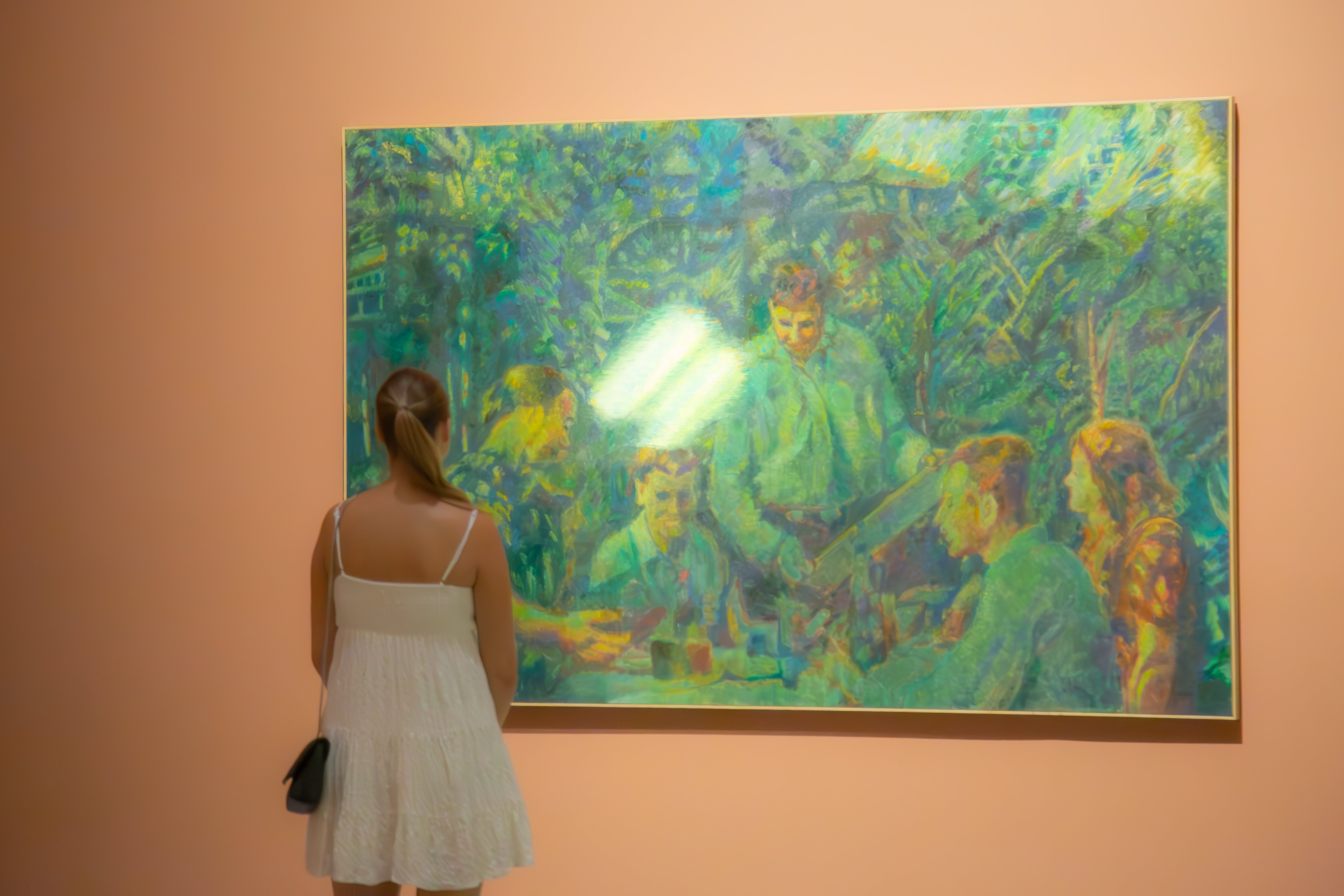 A woman in a white dress gazes at a large colorful painting in a museum. Tel Aviv, Israel